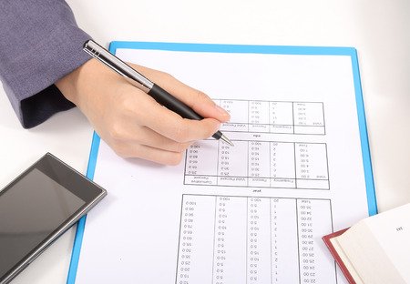 closeup image of business woman holding pen for working on white deskの写真素材