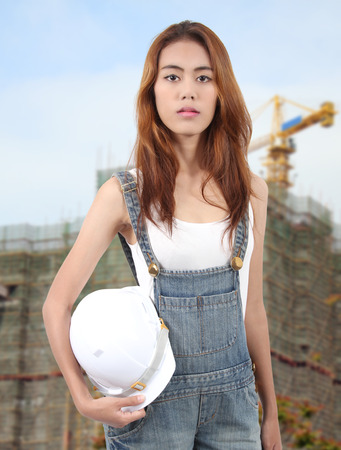 woman worker holding white helmet on hand for a job at workplaceの写真素材