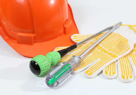Image of helmet gloves and screwdriver for construction on white deskの写真素材