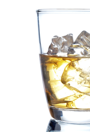Glass of scotch whiskey and ice on a white backgroundの写真素材