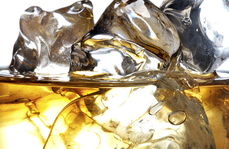 Glass of scotch whiskey and ice on a white backgroundの写真素材