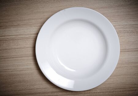 Empty white plate on wooden tableの写真素材