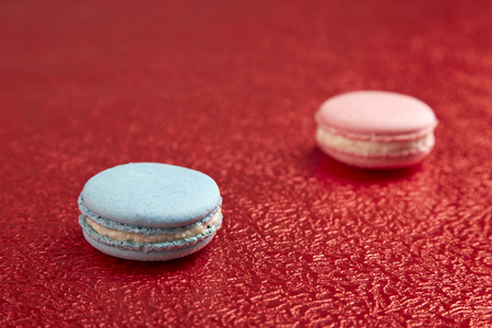Traditional blue and pink French macarons on a red background.の写真素材
