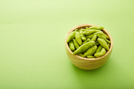 Green pepper wooden bowl on a green background.の写真素材