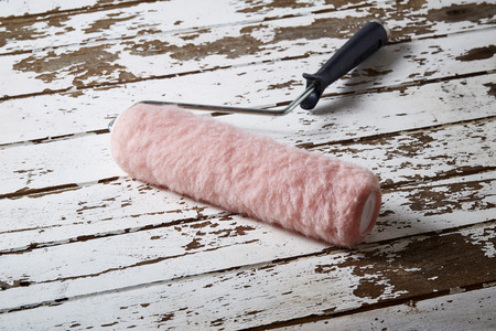 roller with paint on old wood background textureの写真素材