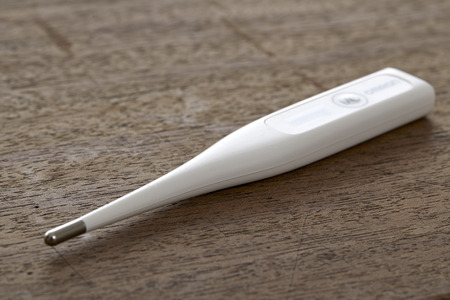 Electronic medical thermometer on wooden background