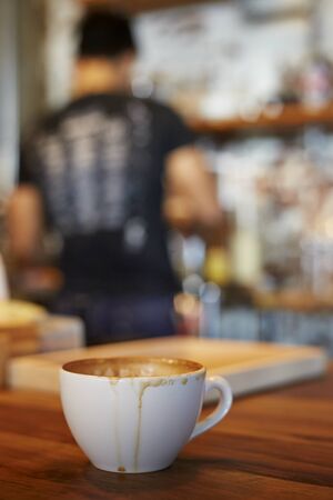 White coffee cup on wooden table with blurred cafe background.の写真素材