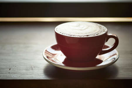 red cup of tasty coffee, isolated on wooden tableの写真素材