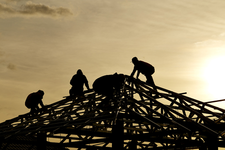 Contractor in Silhouette working on a Roof Top with  Sky in backgroundの写真素材