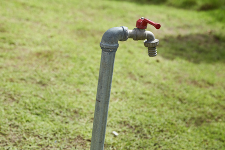 A tap with green grass background / Water consumption and usage conceptの写真素材