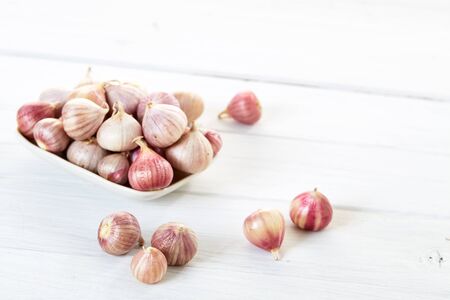 Fresh garlics in ceramic bowl on wooden white table backgroundの写真素材