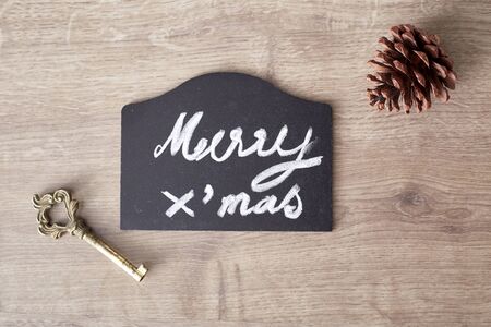 merry christmas text sign with pine cone and key ornament on rustic wooden backgroundの写真素材