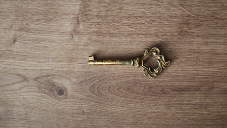 Vintage old rusty key on the wooden boardの写真素材