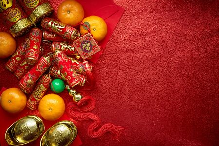 Chinese coins or Chinese knot of luck and chinese firecrackers  and Chinese gold ingots and Traditional chinese knot  (Foreign text means blessing) and Red envelopes and decoration with Fresh oranges on Red Paper background
の写真素材