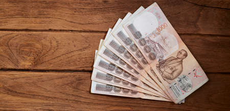 One hundred baht bills on the old wooden