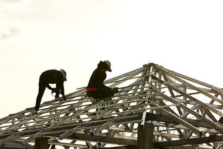 Shot of a carpenter swinging his hammer constructing an roofの写真素材