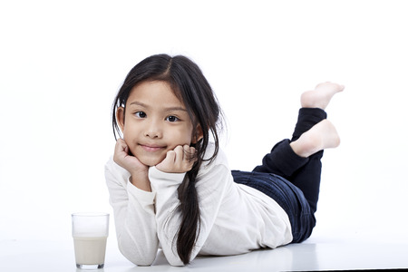 Happy asian girl eating a milk on the floor,education conceptの写真素材