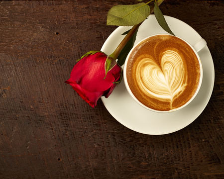 fresh cappuccino with red rose on wood tableの写真素材