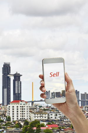 woman hand hold and touch screen smartphone sell building の写真素材
