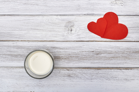 Fresh milk cup and red hearts on white wooden surfaceの写真素材