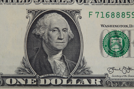 Partial view of a USA one dollar bill showing portrait of George Washington and phrase: This note is...
