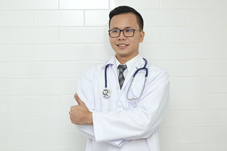 Asian Male Doctor standing In The Hospital Or Office. Medical staff With expert level of expertise.Doctor medical Hospitalize Staff, Insurance ,Business ,Confident, Technology and Healthcare conceptの写真素材