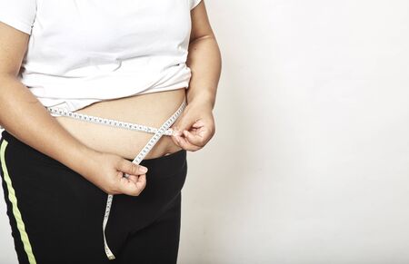 Woman measuring her waistline fat tummy on white background,obese women