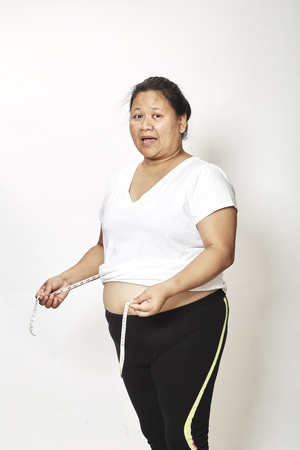 Woman measuring her waistline fat tummy on white background,obese womenの写真素材