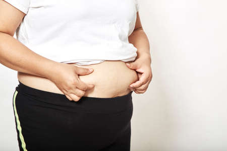 Woman measuring her waistline fat tummy on white background,obese women