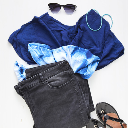 flat lay feminine clothes and accessories collage with jean, sunglasses, earring White wood table backgroundの写真素材