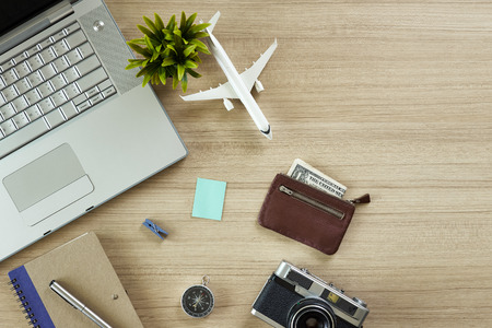 Office wood table with notepad and airplane, computer and tree.  top view with copy space for design. flat layの写真素材