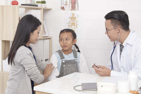 Asian man doctor talking to young child and mother Prevention and Health Care Conceptsの写真素材