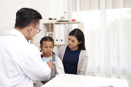Asian man doctor talking to young child and mother Prevention and Health Care Conceptsの写真素材