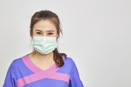 Asians Beautiful young doctor in white medical mask is looking at camera standing white blackground, Medical conceptの写真素材