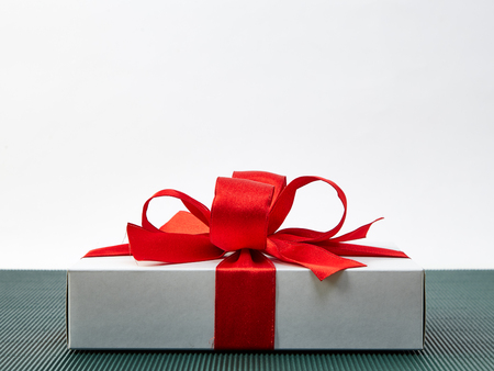 Red ribbon gift box placed on a green background. White back Space for design Sunshine comes from...