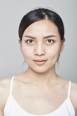 Portrait of gentle pretty woman with healthy skin applying make up painting eyes with brushの写真素材