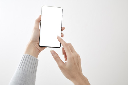 Closeup shot of a woman holding  typing on mobile phone isolated on white background Blank screen to put it on your own webpage or messageの写真素材