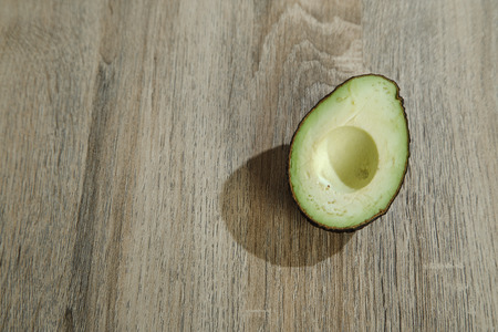 Avocado and avocado  on a wooden background.  Free space for your text. Strong sunlight comes to the right of Light shadowの写真素材