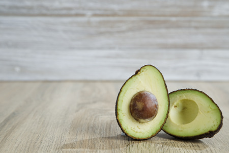 Avocado and avocado  on a wooden background.  Free space for your text. Strong sunlight comes to the...
