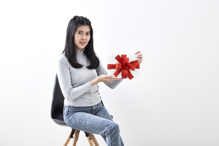 Beautiful sexy young Asian woman gift box sitting in a chair on white background, Picture includes copy spaceの写真素材