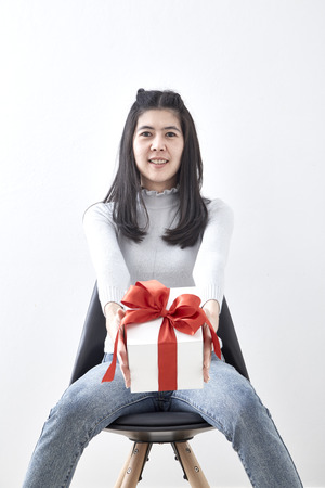 Beautiful sexy young Asian woman gift box sitting in a chair on white background, Picture includes copy spaceの写真素材