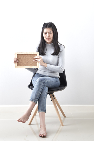 Beautiful young Asian woman Bulletin Board guts pose gesture sitting in a chair on white wall background, Picture includes copy space, For the holiday background design. discount Businessの写真素材
