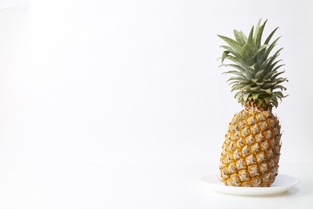 ripe pineapple in white plate isolated studio shoot on white background, Light emulates natural light with space for design.の写真素材