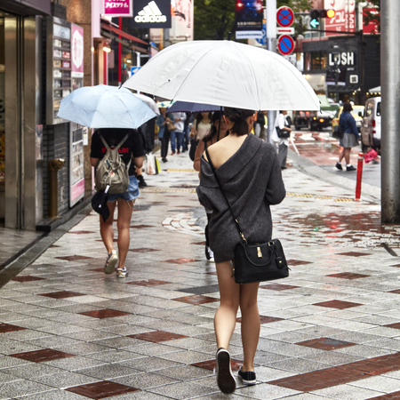 Tokyo, Japan Sep 21 2018 Beautiful young woman. Attractive beautiful lady hold an umbrella. Itâs rainy day. Lovely girl is walking at city when light rain. Itâs rainy season. She look so relaxed and happy. copy spaceのeditorial素材