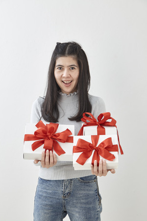 Young Asian woman show OK with a gift box on bright gray wall backgroundの写真素材