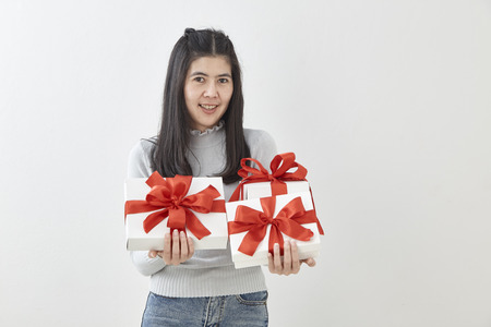 Young Asian woman show OK with a gift box on bright gray wall backgroundの写真素材