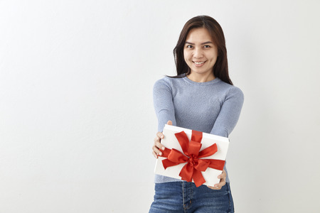 Young Asian woman show OK with a gift box on bright gray wall backgroundの写真素材