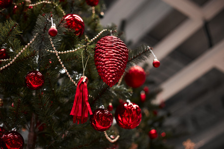 Closeup of red bauble hanging from a decorated Christmas tree.