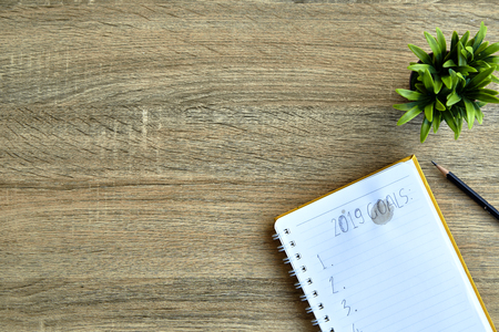 Top view of 2019 goals on notebook on old wood table
