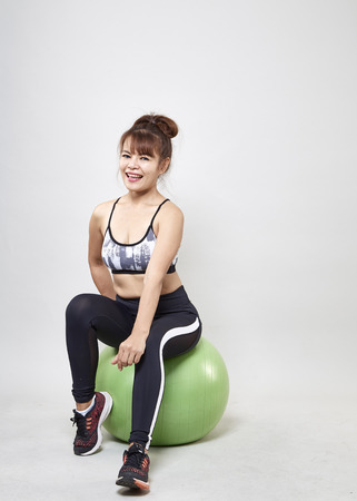 Beautiful Asian woman sitting on balloon exercise for perfect body.の写真素材